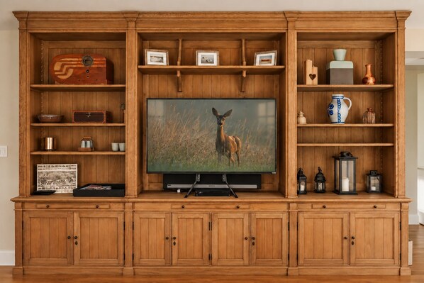 A wooden entertainment center with a television, shelves with decorative items, and storage cabinets.