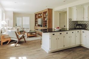 Una cucina moderna con mobili bianchi, un'isola in legno e un'area pranzo con divano e sedie.