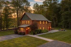 A two-story log cabin with a well-maintained lawn and a fire pit area.