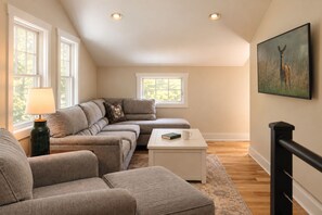 A living room with a sectional sofa, a coffee table, and a painting on the wall.