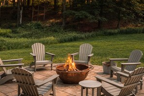 A fire pit with chairs arranged around it on a patio.