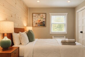 A bedroom with a bed, nightstand, lamp, and a window with blinds.