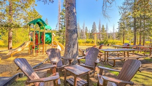 A park with wooden Adirondack chairs, picnic tables, and a playground. - Woodland Retreat with Private Multi-Level Deck & Backyard Creek (Truckee)
