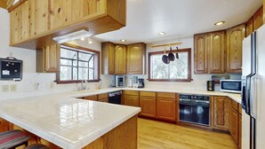 A kitchen with wooden cabinets, a tiled island, and modern appliances. - Rustic home with wood stove, deck, open floor plan, & nearby activities (Carnelian Bay)