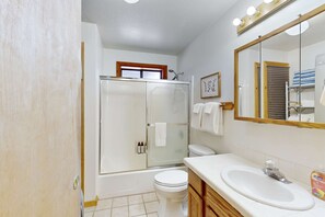 A bathroom with a shower, toilet, sink, and a mirror. - Rustic home with wood stove, deck, open floor plan, & nearby activities (Carnelian Bay)