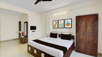 A bedroom with a bed, a wardrobe, a TV, and artwork on the wall.