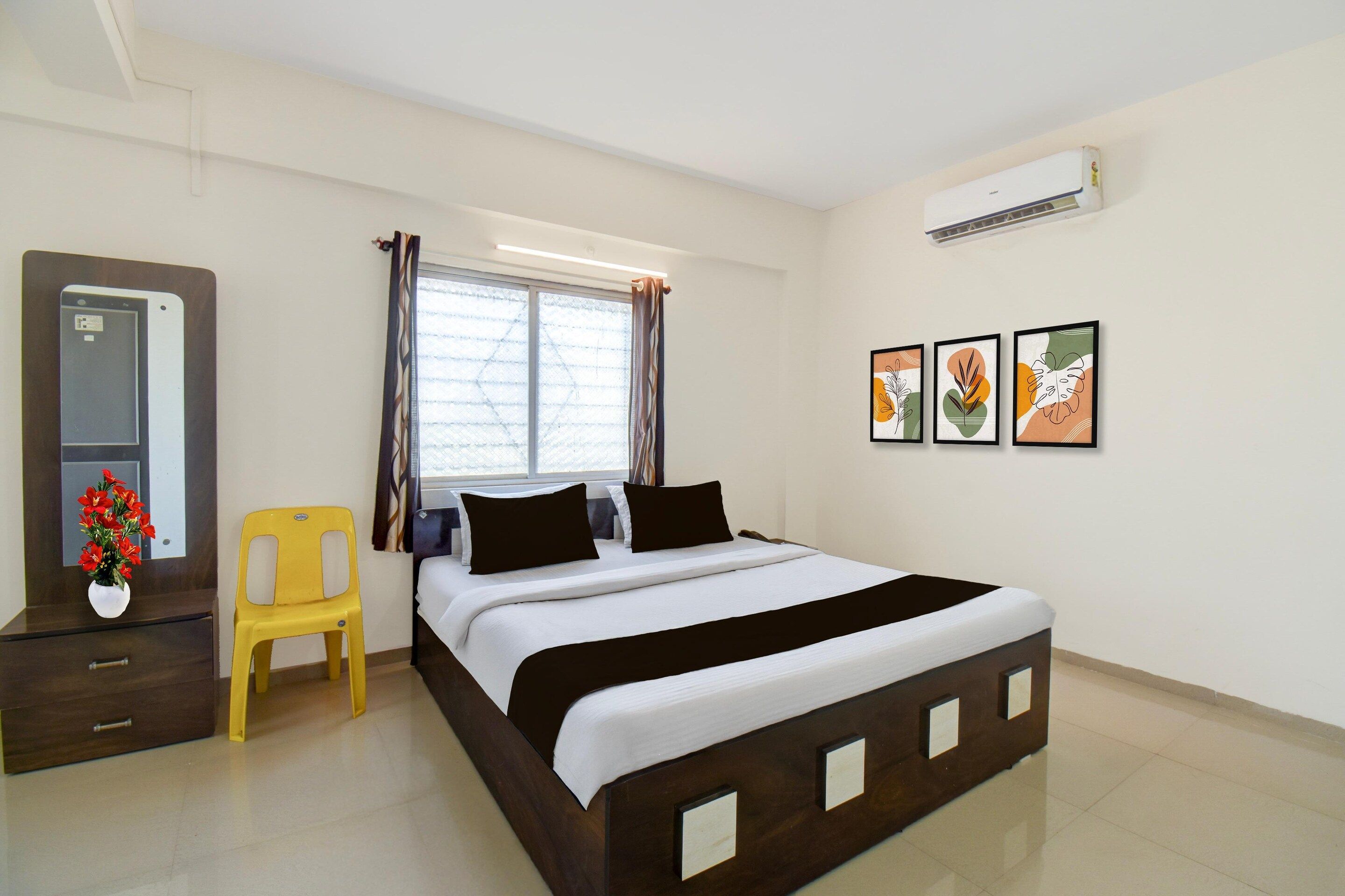 A bedroom with a bed, a chair, a dresser, a window with curtains, and wall art.