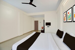 A hotel room with a large bed, a ceiling fan, a flat-screen TV, and artwork on the wall. - Classic With Balcony Hotel Galaxy Inn (Junnar)