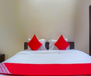 A bed with white bedding and two red pillows.