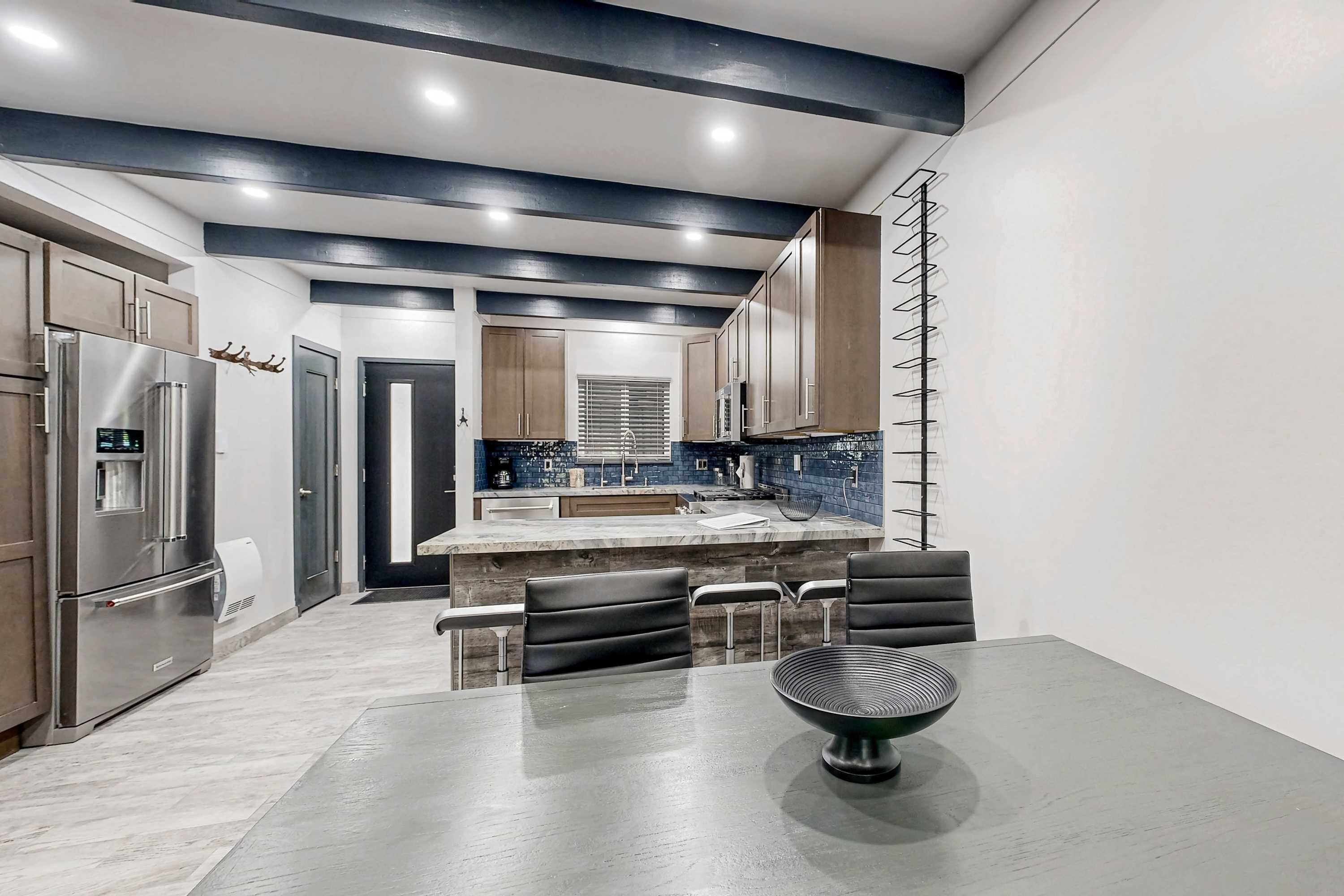Una cocina moderna con una isla central, electrodomésticos de acero inoxidable y una zona de estar con una mesa redonda.