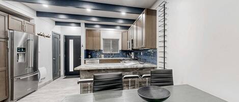 Una cocina moderna con una isla central, electrodomésticos de acero inoxidable y una zona de estar con una mesa redonda.