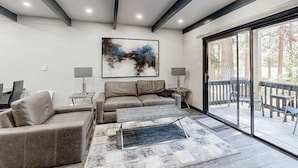 A modern living room with a sofa, coffee table, and a large window. - Sleek condo with deck, BBQ, board games, and streaming (Incline Village)