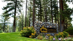 A stone sign with 'Championship Golf Course' text and a mountain logo, surrounded by a well-maintained grassy area and flowering plants. - Sleek condo with deck, BBQ, board games, and streaming (Incline Village)