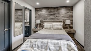 A bedroom with a large bed, two bedside tables with lamps, a mirror, and a wardrobe. - Sleek condo with deck, BBQ, board games, and streaming (Incline Village)
