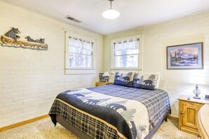 A bedroom with a bed, two windows, a wall-mounted shelf with bear figurines, a nightstand, a lamp, and a framed picture. - Basecamp on Aspen (South Lake Tahoe)
