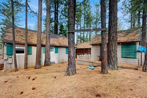 Ein rustikales Blockhaus mit einem Reetdach, umgeben von hohen Kiefern.