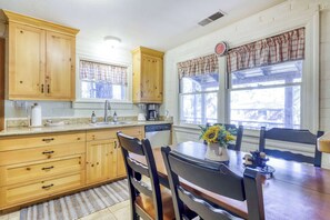 A kitchen with wooden cabinets, a sink, and a dining area with a table and chairs. - Basecamp on Aspen (South Lake Tahoe)