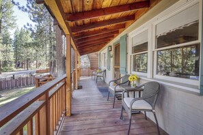 A wooden deck with outdoor seating and a covered area, overlooking a forested area. - Basecamp on Aspen (South Lake Tahoe)