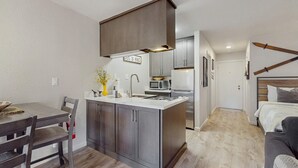 A compact kitchen with a central island, a dining area with a table and chairs, and a bedroom with a bed and a headboard. - Cozy Studio with Full Kitchen, Grill, Fireplace w/Access to Pool, Spa, Game Room (Tahoe Vista)