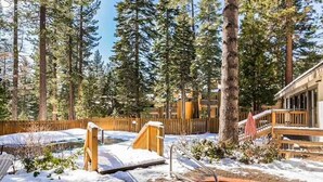 A pool surrounded by a wooden deck, with a wooden fence and tall trees in the background. - Cozy Studio with Full Kitchen, Grill, Fireplace w/Access to Pool, Spa, Game Room (Tahoe Vista)
