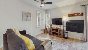 A living room with a sofa, a ceiling fan, a TV, a fireplace, and a window with blinds. - Cozy Studio with Full Kitchen, Grill, Fireplace w/Access to Pool, Spa, Game Room (Tahoe Vista)