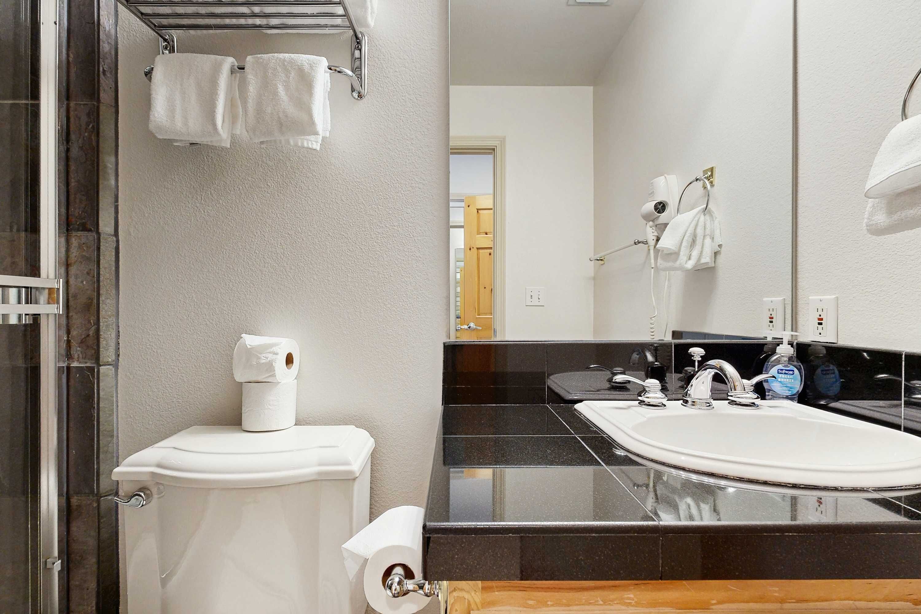 Een badkamer met een toilet, een wastafel, een spiegel en een douchehoek.