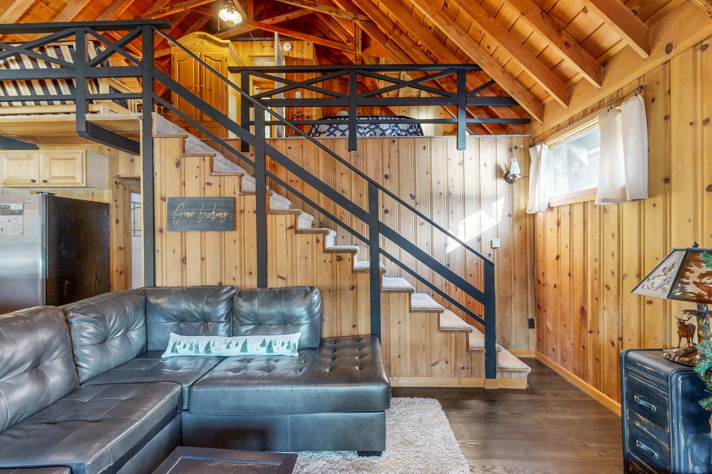 Un intérieur en bois avec un canapé en cuir, un escalier et un coin cuisine.
