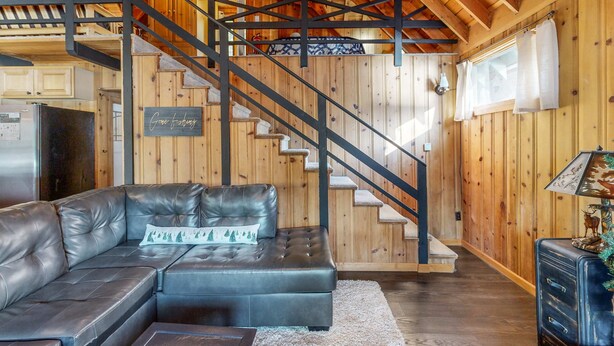 Un interior de madera con un sofá de cuero, una escalera y una zona de cocina.
