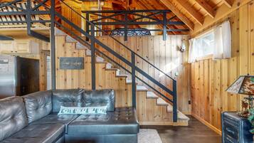 Un intérieur en bois avec un canapé en cuir, un escalier et un coin cuisine.