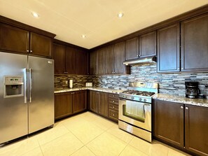 A modern kitchen with dark wood cabinets, stainless steel appliances, and a tiled backsplash. - Waterfront Bright and Spacious Getaway (Innisfil)