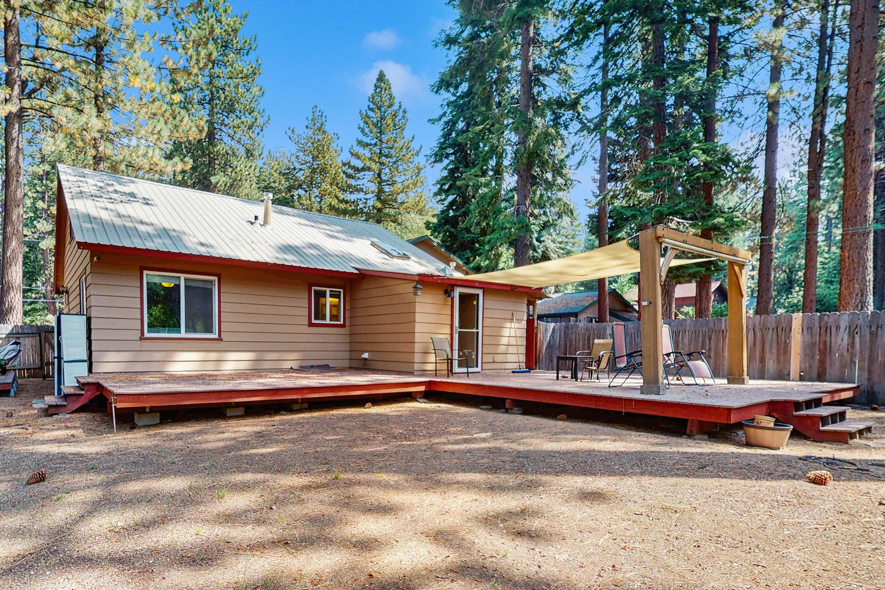 A single-story house with a covered patio, a fenced yard, and a wooden deck.