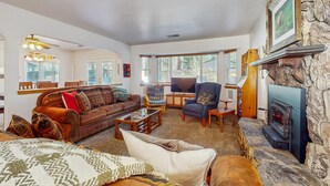 A cozy living room with a fireplace, a sofa set, a television, and a stone accent wall. - Charming Pet Friendly Home with Hot Tub, Enclosed Yard, Short Walk to Beach (South Lake Tahoe)
