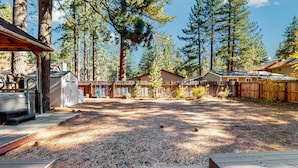 A wooden deck, a barbecue grill, and a fenced yard with cabins. - Charming Pet Friendly Home with Hot Tub, Enclosed Yard, Short Walk to Beach (South Lake Tahoe)