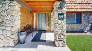 A stone-clad building with a wooden porch, a number '55' sign, and a metal bench. - Family-Friendly townhouse near lake - convenient & walkable location (Incline Village)