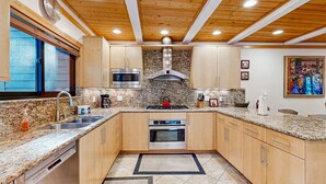 A kitchen with granite countertops, wooden cabinets, stainless steel appliances, and a wooden ceiling. - Comfortable Townhome with Pool, Deck, & Lovely Sunsets - Walk to Lake (Kings Beach)