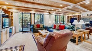 A spacious living area with a wooden ceiling, large windows, and a fireplace. - Comfortable Townhome with Pool, Deck, & Lovely Sunsets - Walk to Lake (Kings Beach)