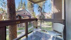 Un balcon avec une chaise en métal, une table en métal et une vue sur des maisons et des arbres.