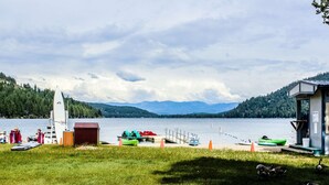 En plats vid en sjö med en brygga, båtar och en liten byggnad.