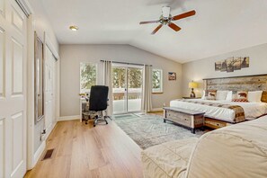 Ein Schlafzimmer mit einem Bett, einem Schreibtisch, einem Sessel, einem Deckenventilator und Blick durch die Glastüren.