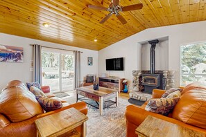 A cozy living room with leather sofas, a wooden coffee table, a fireplace, and a ceiling fan. - Cozy Tahoe Vista home with fireplace, furnished deck, & forest view (Tahoe Vista)