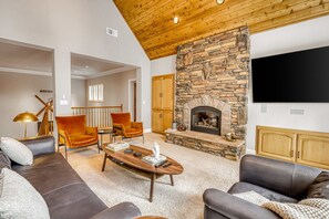 Ein modernes Wohnzimmer mit Kamin aus Stein, Ledersofas, einem Holztisch und einem flachbildfernseher, der an der Wand montiert ist.