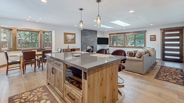 A spacious kitchen with a central island, dining area with chairs, a sofa, and a television. - Beautiful home with private hot tub, gazebo, and gas fireplace (South Lake Tahoe)
