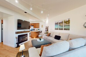 A modern living room with a fireplace, a sofa, a coffee table, and a TV. - Waterfront townhouse with dock & mountain view - close to skiing, hiking & beach (South Lake Tahoe)