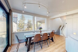 A dining area with a wooden table, four chairs, a vase with flowers, and a staircase leading to another level. - Waterfront townhouse with dock & mountain view - close to skiing, hiking & beach (South Lake Tahoe)