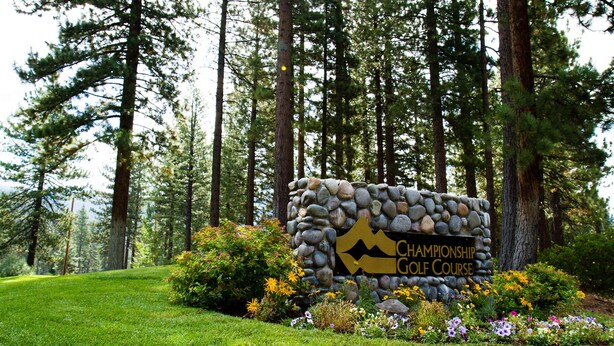 Kivestä tehty kyltti, jossa lukee ”Championship Golf Course”, ja sen ympärillä on hyvin hoidettu nurmikko ja kukkivia kasveja.