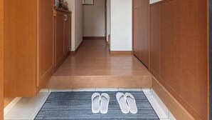 Un pasillo con armarios de madera, un refrigerador pequeño y un par de pantuflas sobre una alfombra.