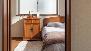 Un dormitorio con cama, mesita de noche, cómoda, ventana y lámpara en el techo.