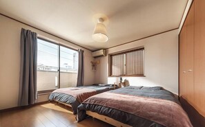 Une chambre avec deux lits, une fenêtre avec des rideaux, un luminaire au plafond et une armoire en bois.