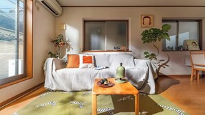 Una sala de estar acogedora con un sofá, una mesita de madera y un ventanal grande.
