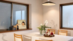Un comedor con una mesa, sillas, una lámpara colgante y una ventana con un marco de foto.